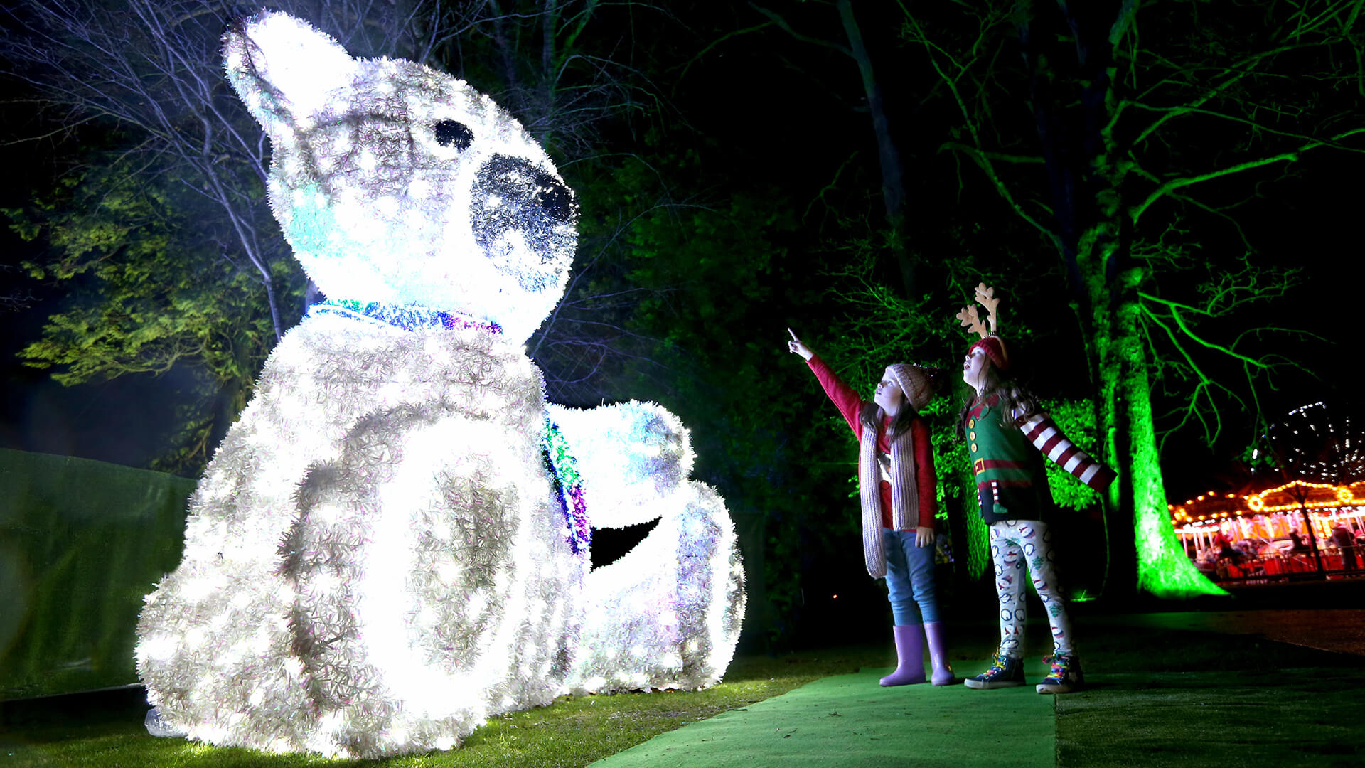 Giant festive light up teddy bear with two children looking in awe