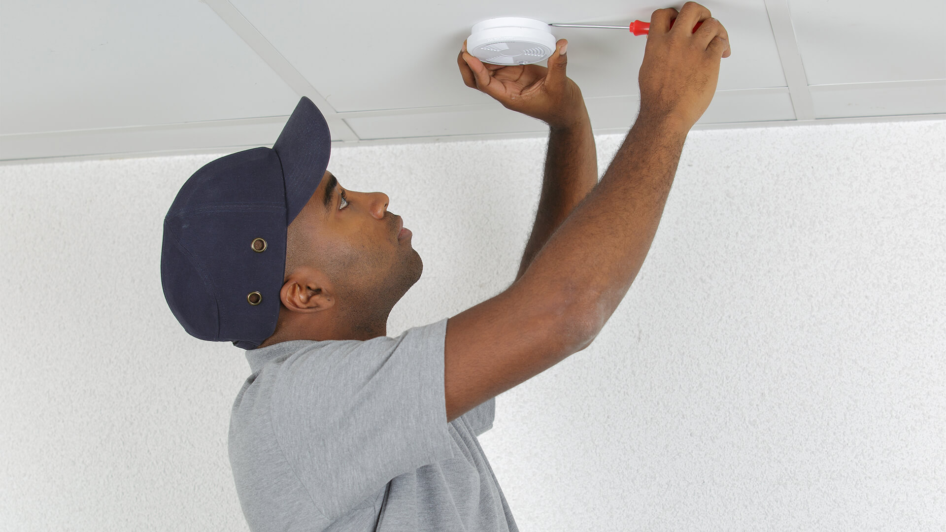 Man fixing a ceiling fire alarm